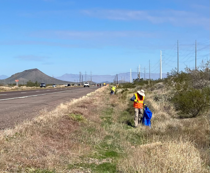 Someone picking up litter along the highway.