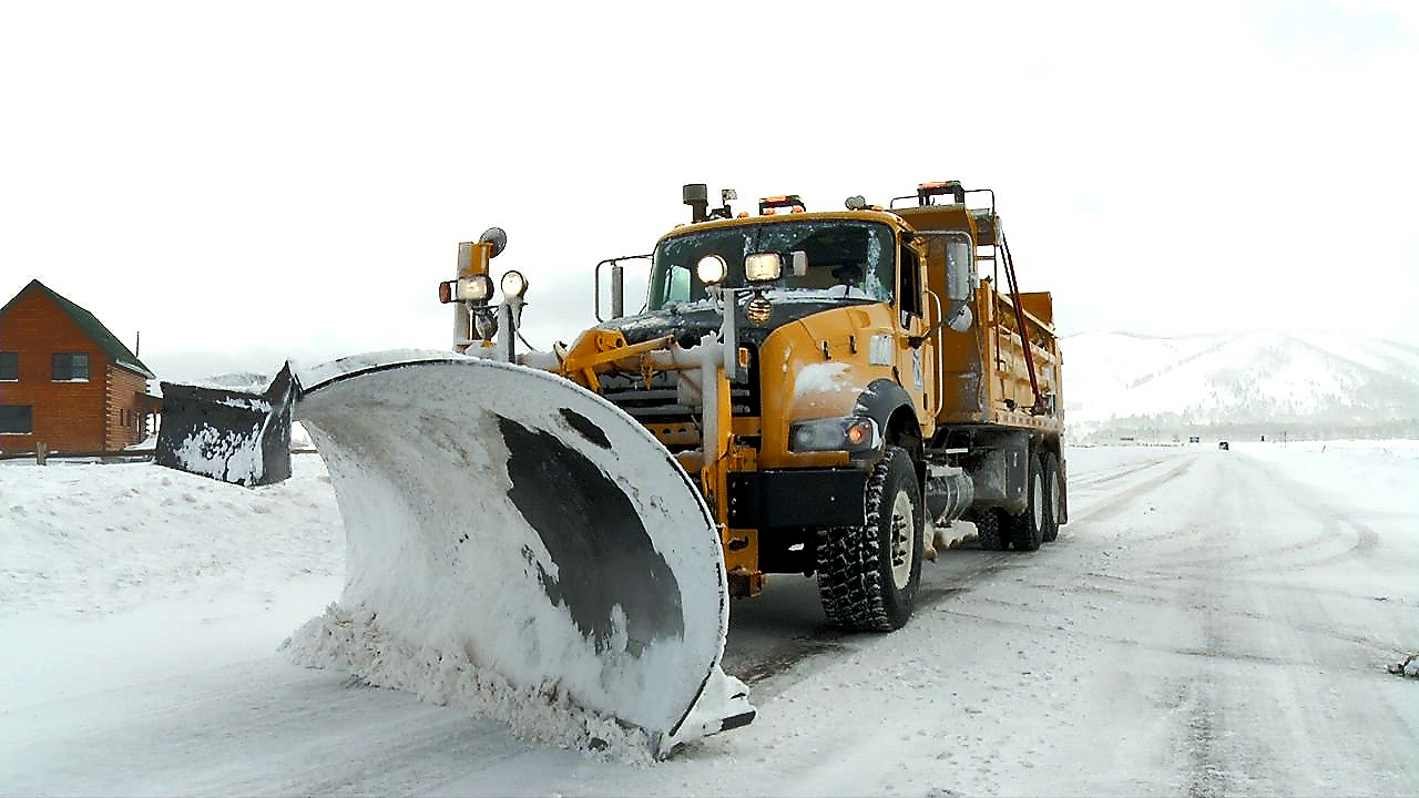 Snowplow works down a snowy road.