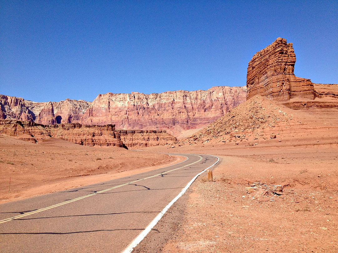 Desolate roadway towards rock cliffs and formations.