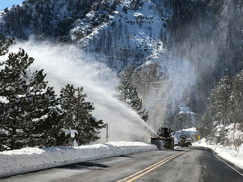 Slow blower clears snow from the side of the road.