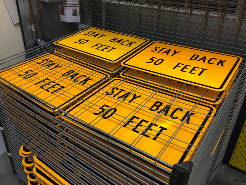 Four stacks of "Stay Back 50 Feet" signs.