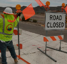 Worker by a road closed sign