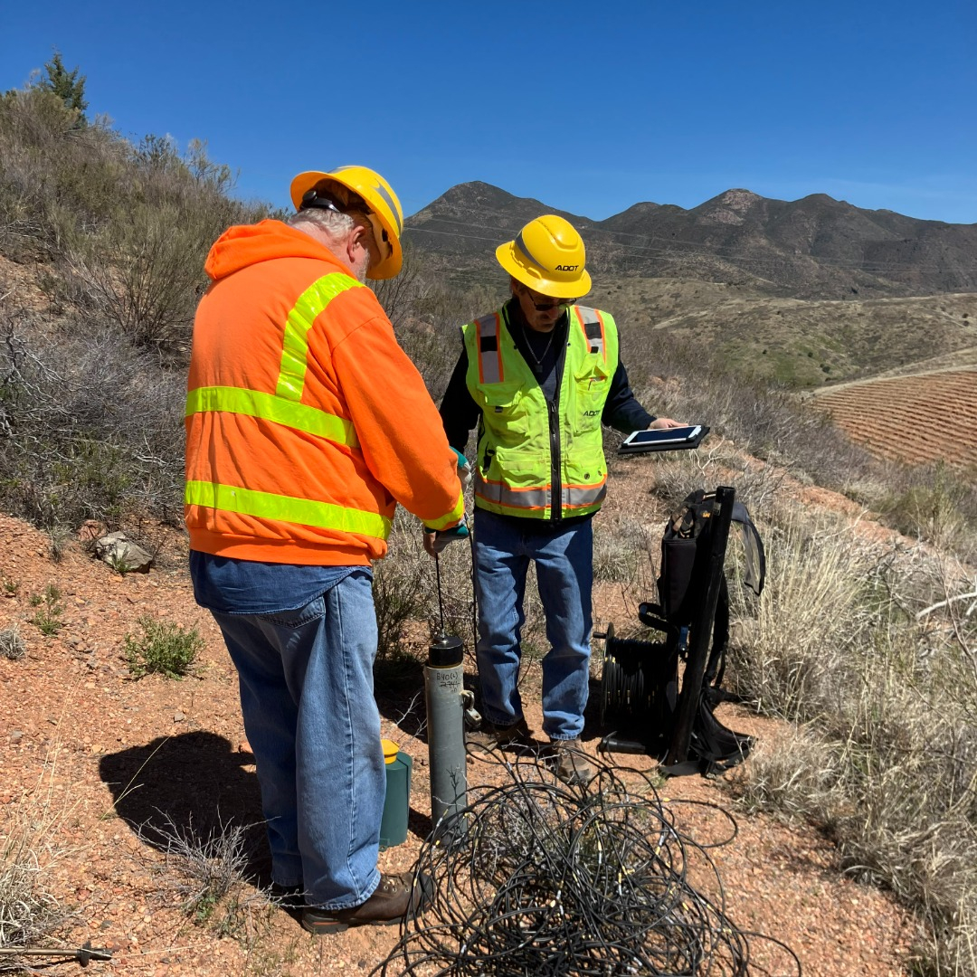 Two ADOT geotechs use an inclinometer on a hillside to measure the area's stability.