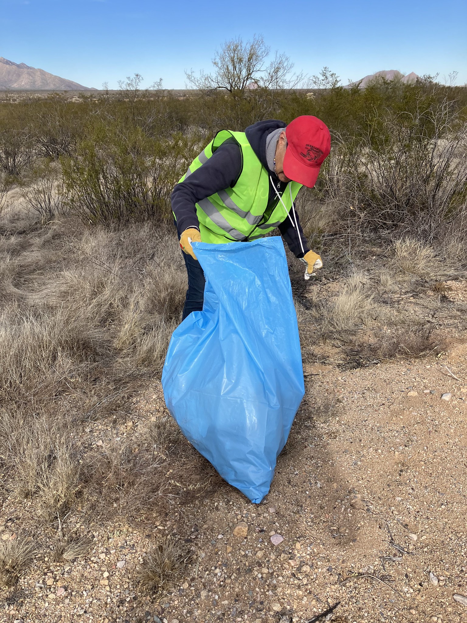 A volunteer collects litter from a highway roadside.