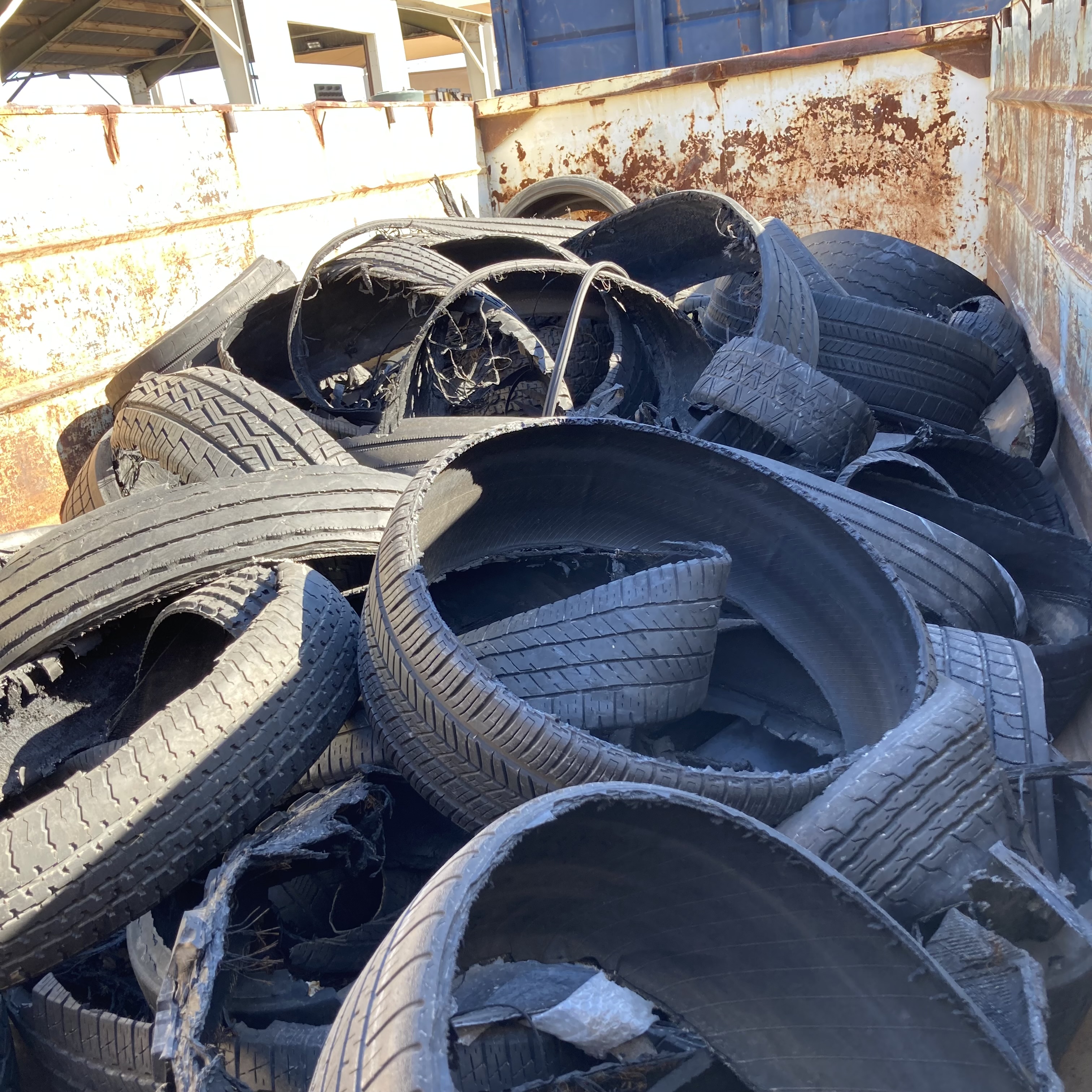A dumpster is filled with shredded and blown-out tires.