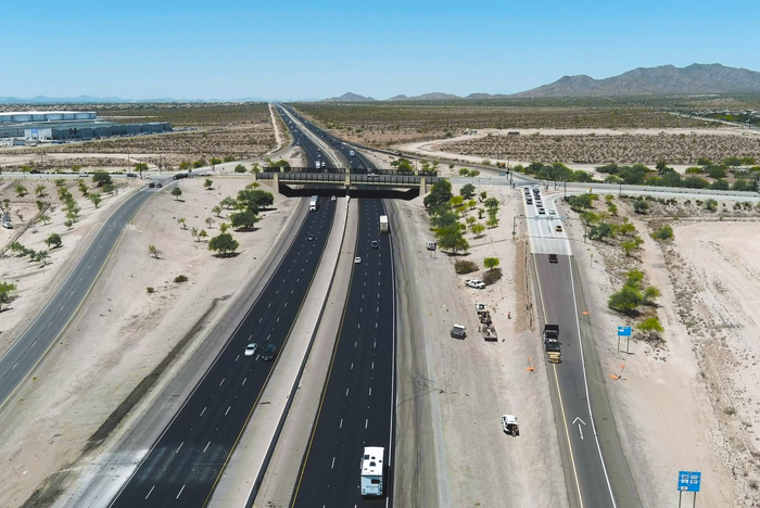 A multi-lane interstate highway cuts through a desert landscape.