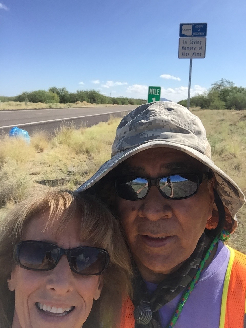 Two people standing in front of an Adopt a Highway sign on State Route 86