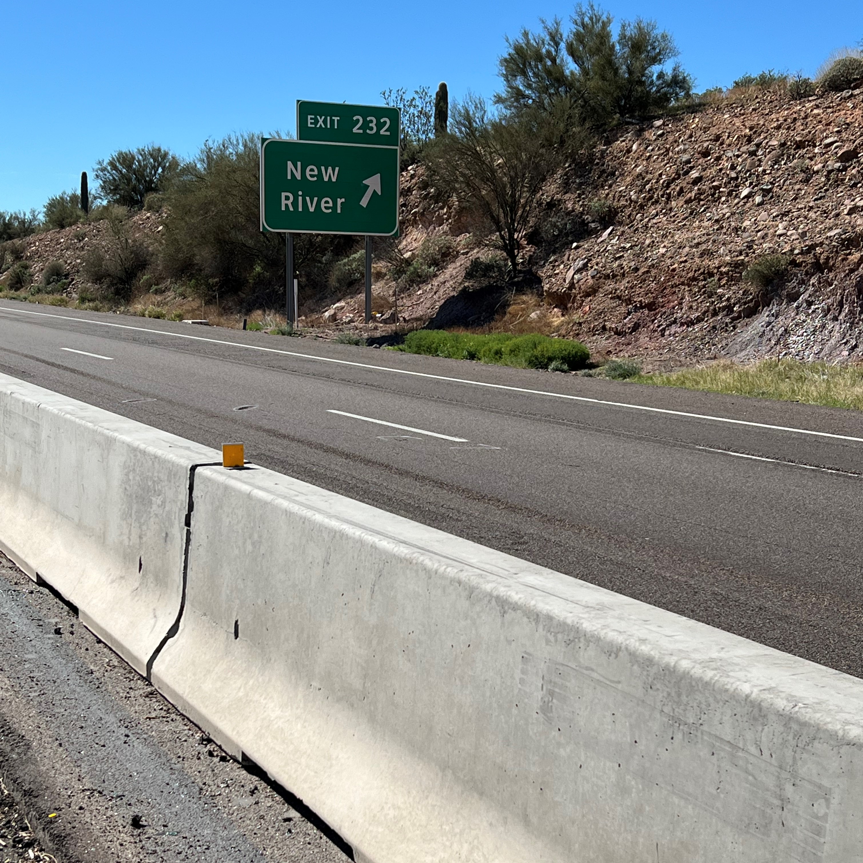 Interstate 17 near the New River exit. A paved roadway with a barrier in the foreground. On the other side of the barrier are where the new flex lanes are being constructed.