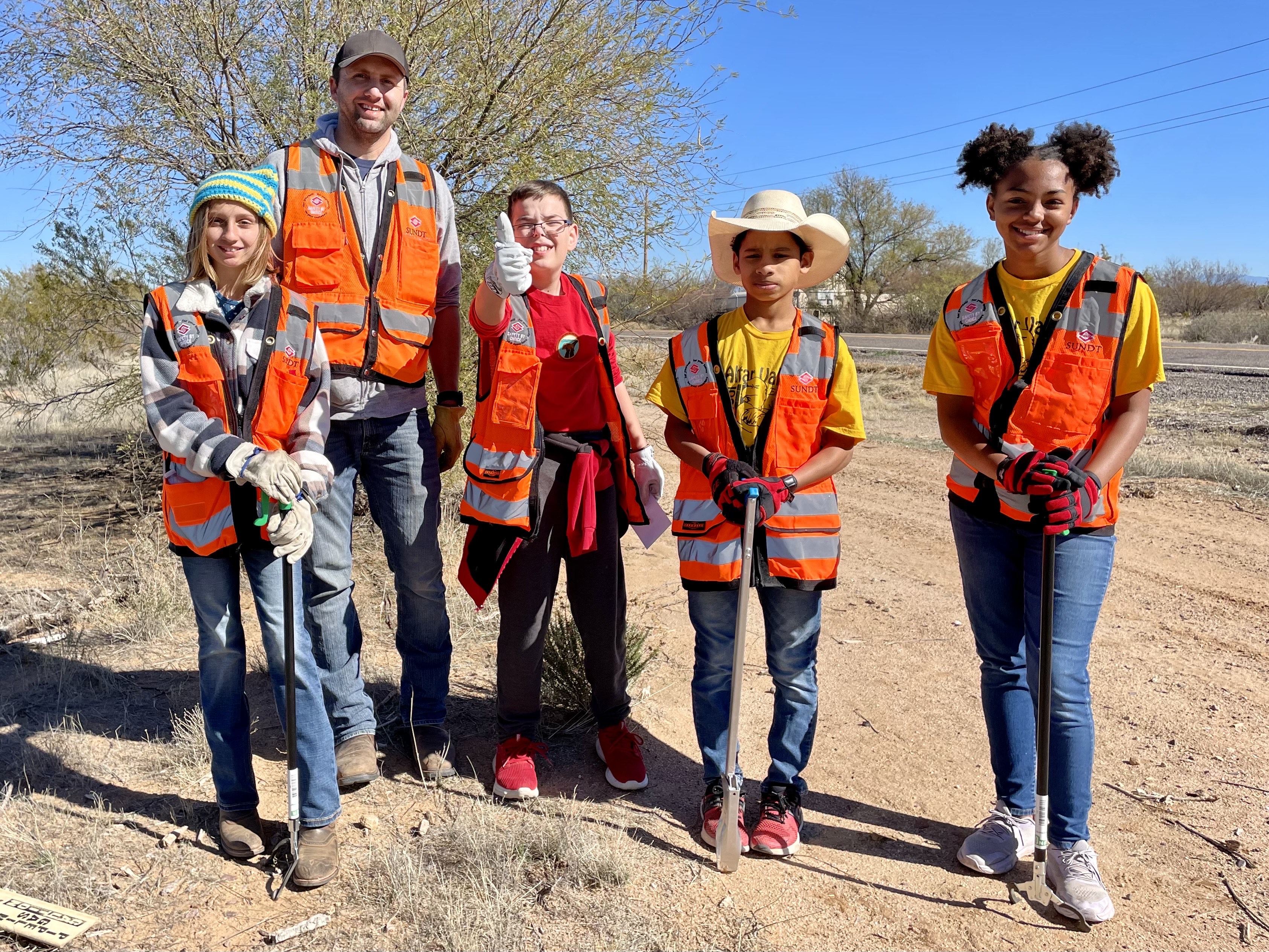Five people dressed in orange vests volunteering to clean up the highway