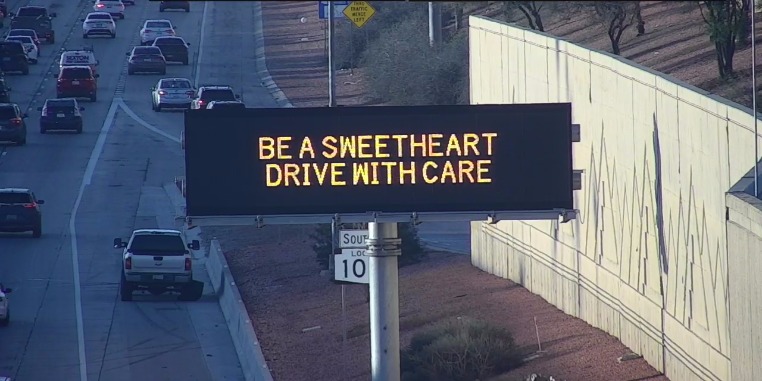 A digital message board on a highway displays a safety message.