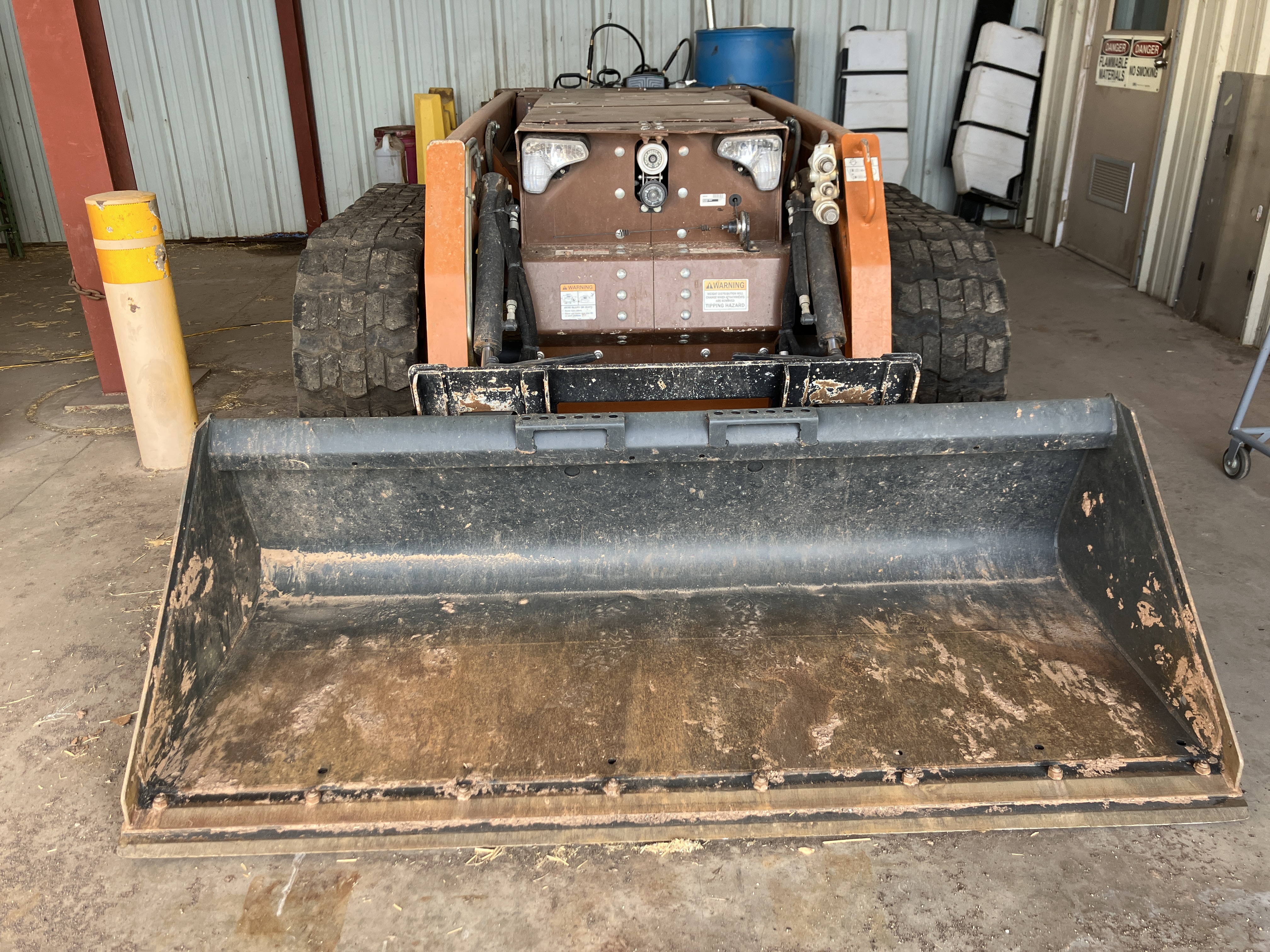A remotely-controlled skid steer is parked in an equipment garage.