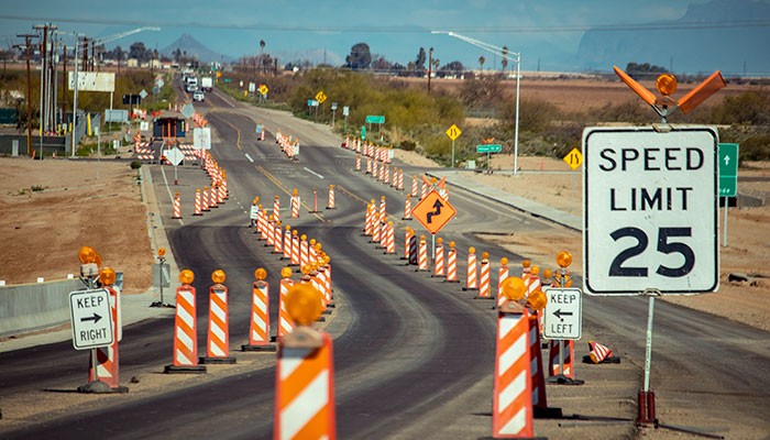 A highway work zone with orange traffic control devices.
