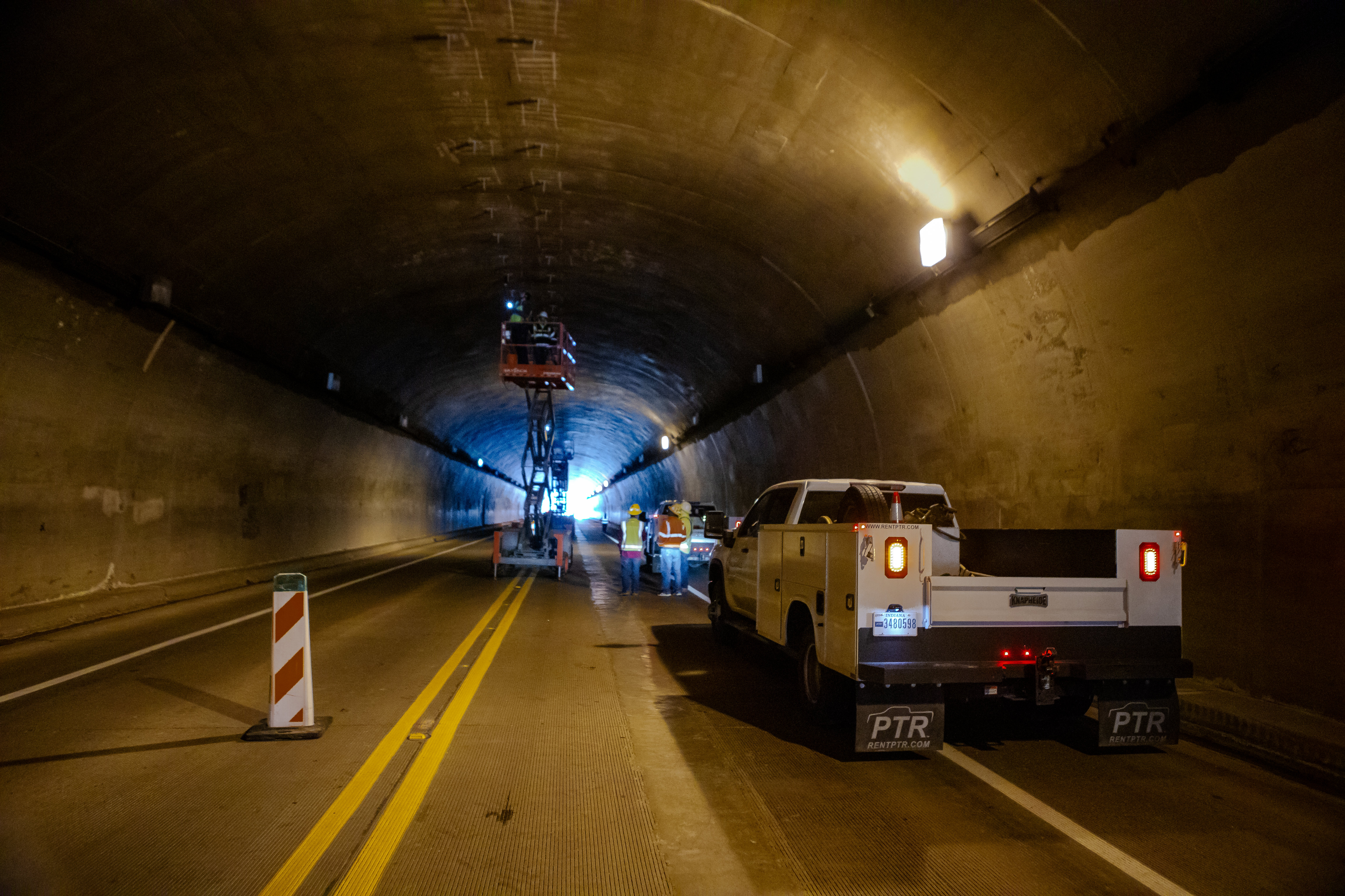 A work truck is parked inside a tunnel as construction work occurs inside the tunnel.