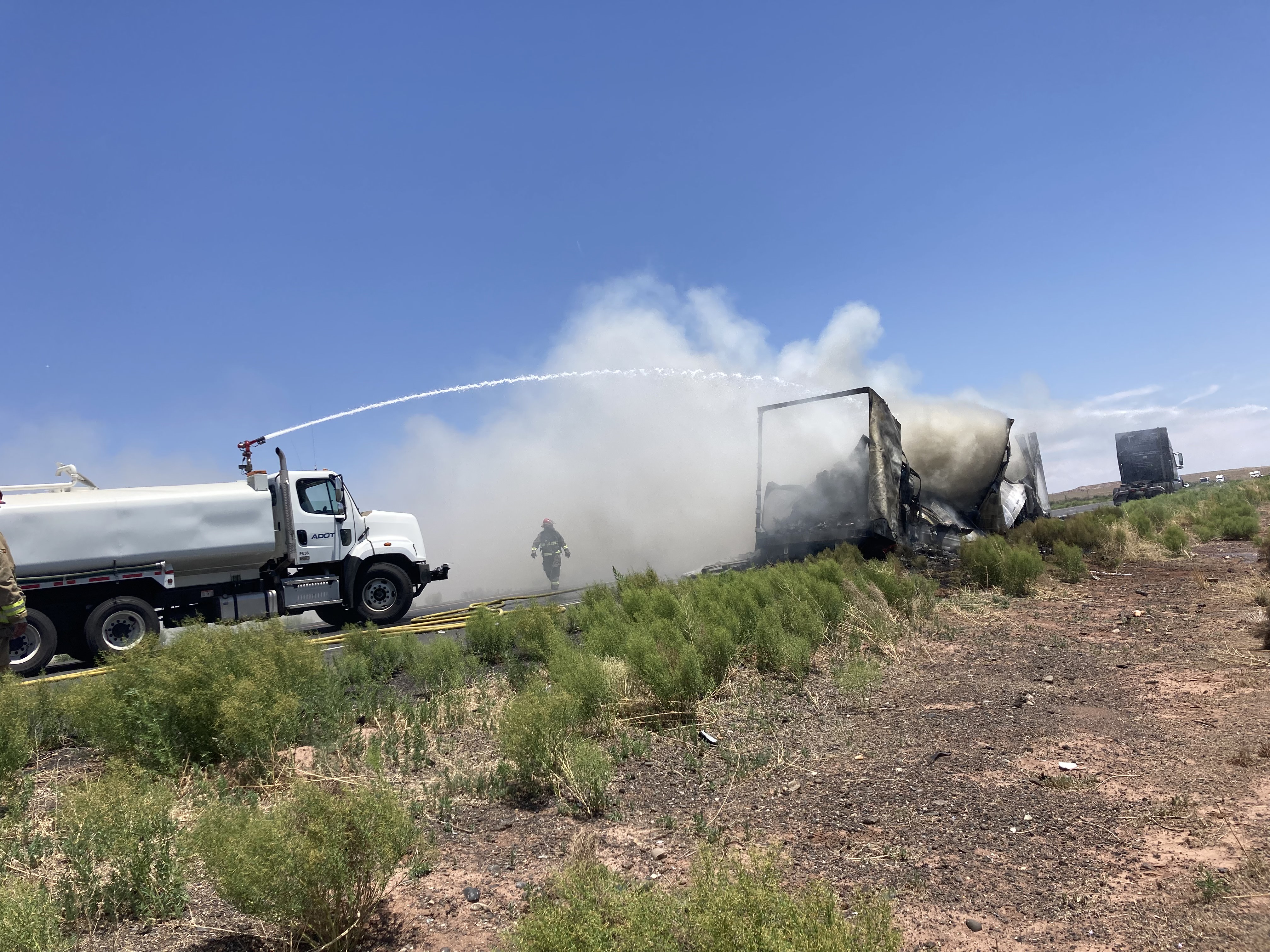 A water tanker puts out a vehicle fire on the highway