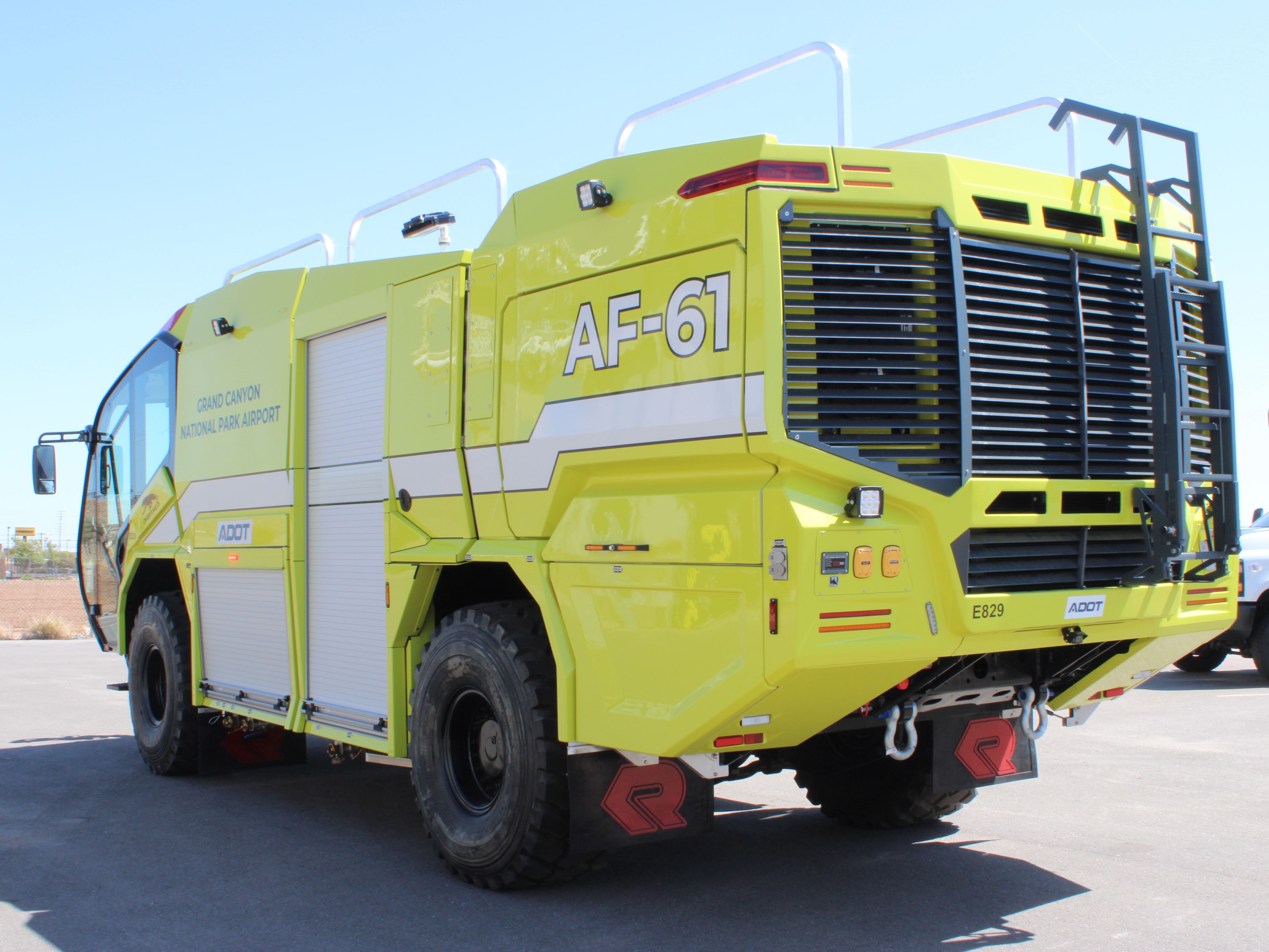 A yellow airport fire truck, labeled AF-61, is parked on asphalt under a clear sky.