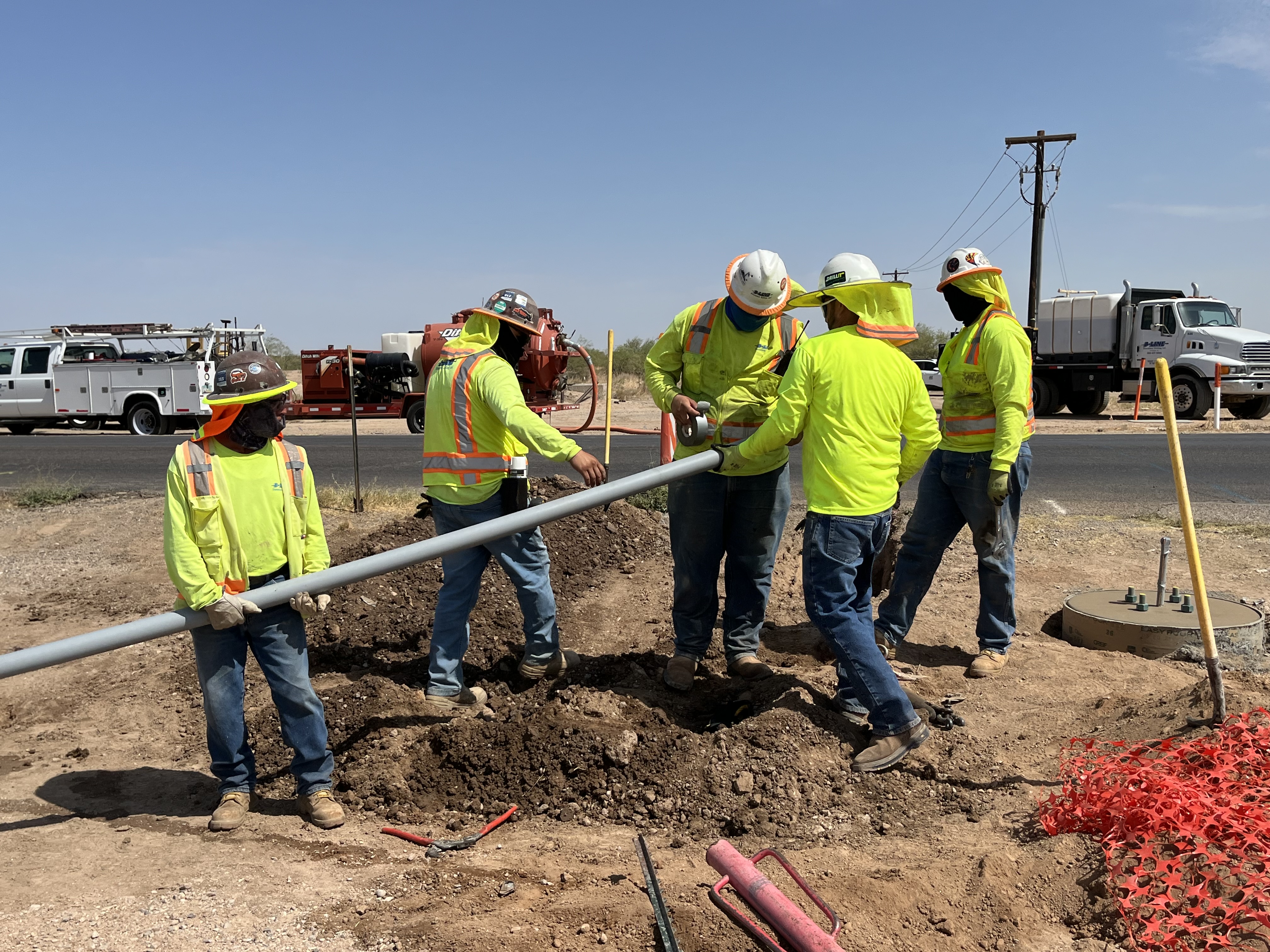 Construction workers moving a pipe in Eloy