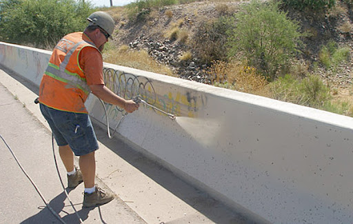 ADOT crew member is removing graffiti on overpass road