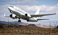 A white commercial airplane taking off from a runway with mountains and desert landscape in the background.