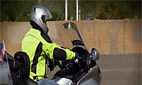 A motorcyclist in a neon yellow jacket and helmet rides a motorcycle.