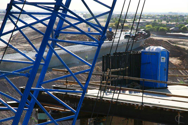Blue construction crane and blue portable restroom