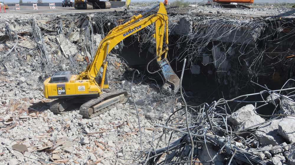 Cable, rebar, concrete and yellow backhoe.