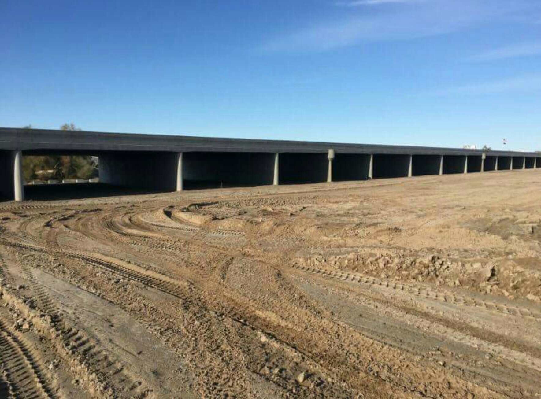 The new Fortuna Wash Bridge spans a dirt construction site under a clear blue sky.