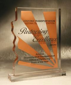 Clear glass award shaped like Arizona, engraved with Partnering Excellence Award and transportation details.