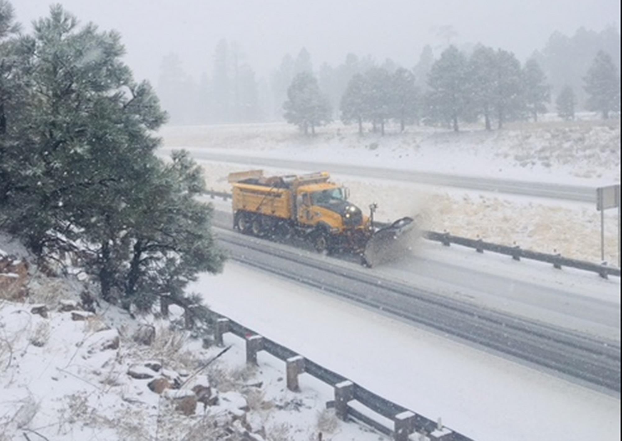 ADOT snowplow at work along snow-covered freeway