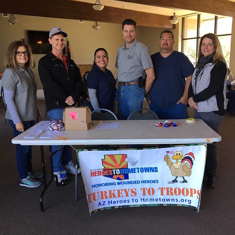 Six people standing behind a table with a banner that says Turkeys for troops