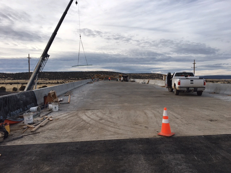 Construction scene at the West Seligman Bridges on Interstate 40 with a crane, equipment, traffic cone, and a white pickup truck.