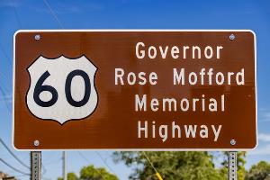 Brown road sign reads: 60 Governor Rose Mofford Memorial Highway against a blue sky.