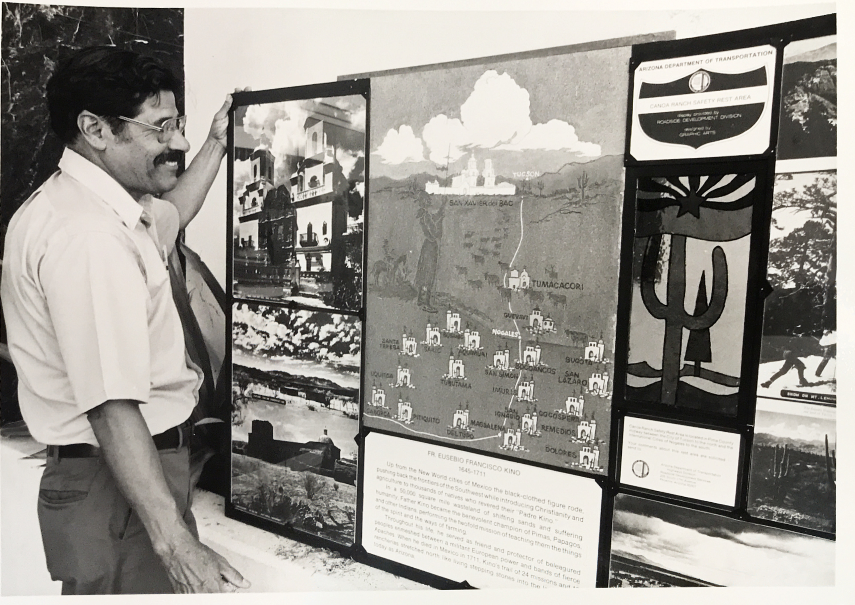 Black and white image of man looking at display board
