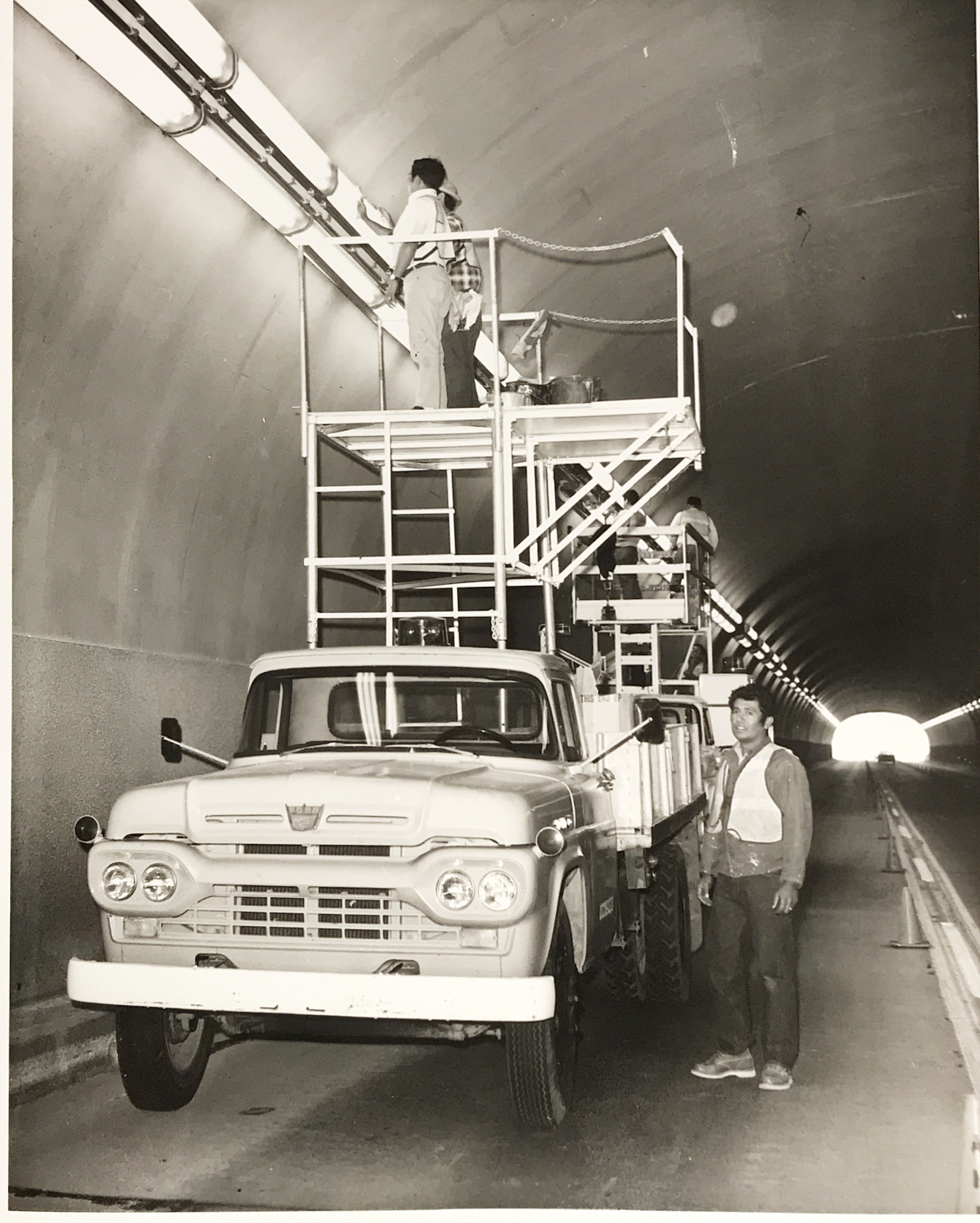 Black and white photo of workers replacing lights in the Queen Creek Tunnel