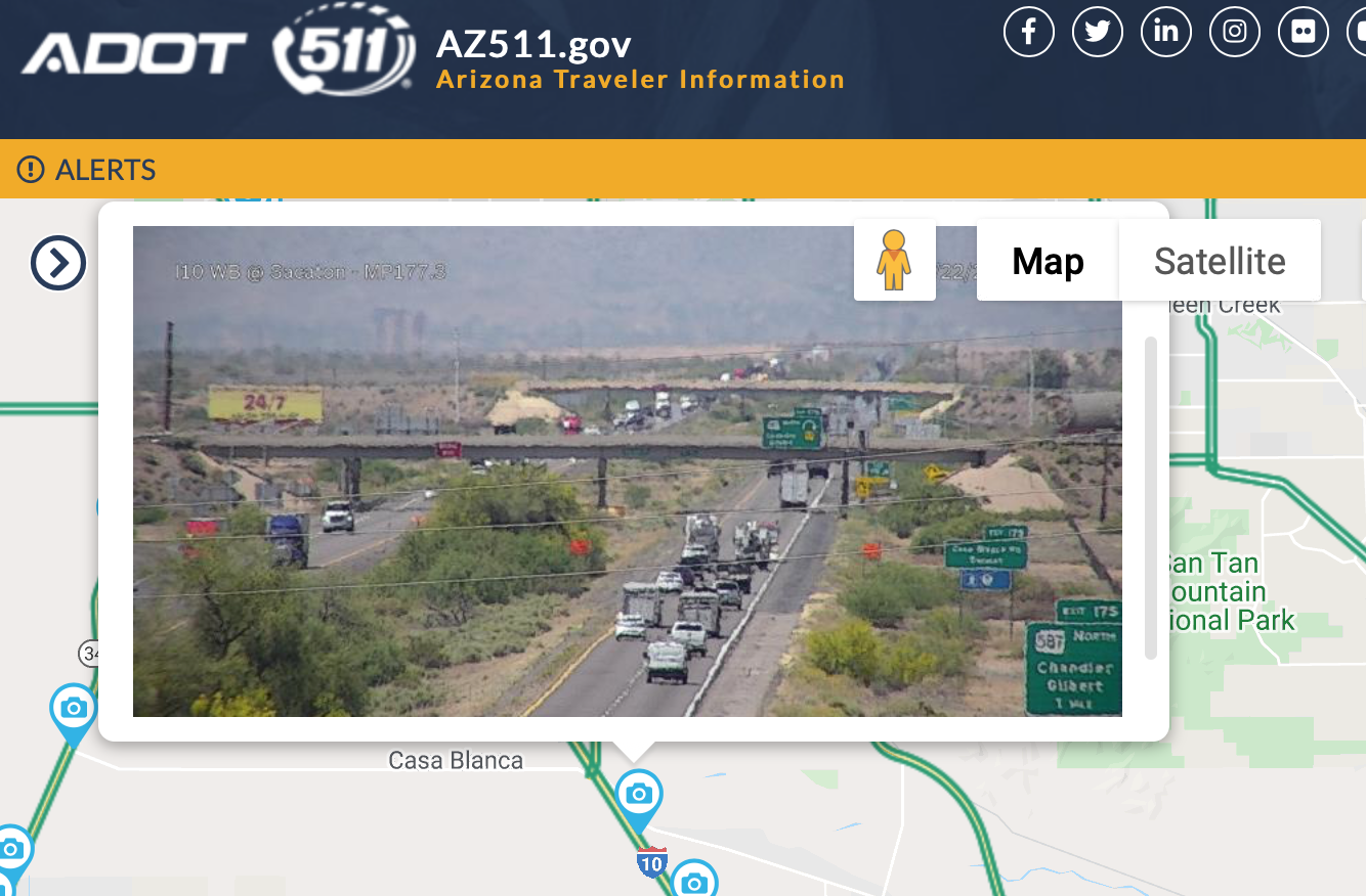 Traffic camera view of a busy highway in Arizona with cars, trucks, and desert landscape in the background.