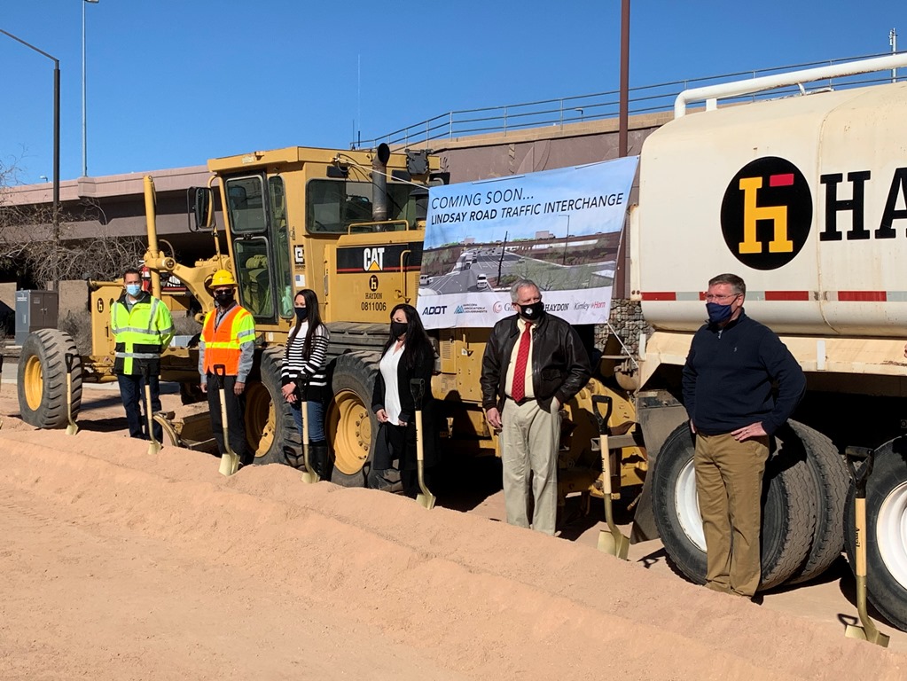 Groundbreaking participants in front of large trucks