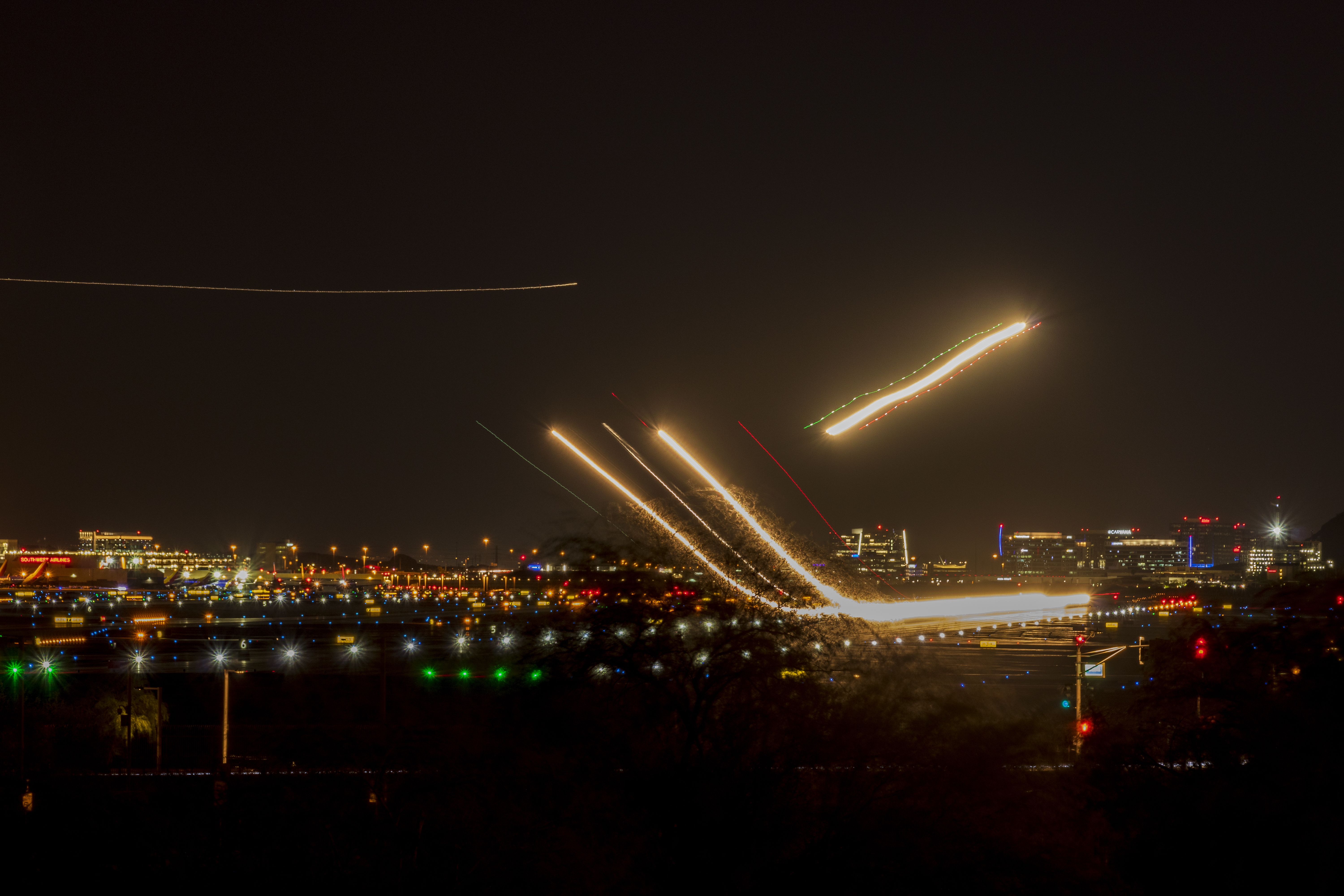 Airplanes taking of at night with streams of light visible