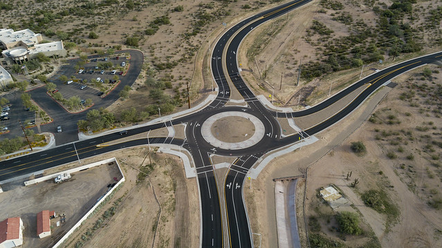 Aerial view of a large roundabout with four roads in a desert landscape.