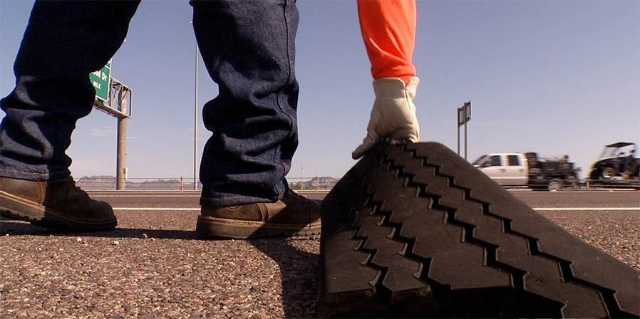 Worker removes tire tread from side of freeway