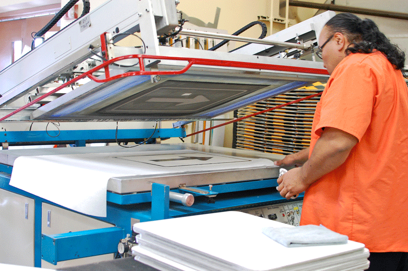Worker uses printing machine in ADOT sign shop