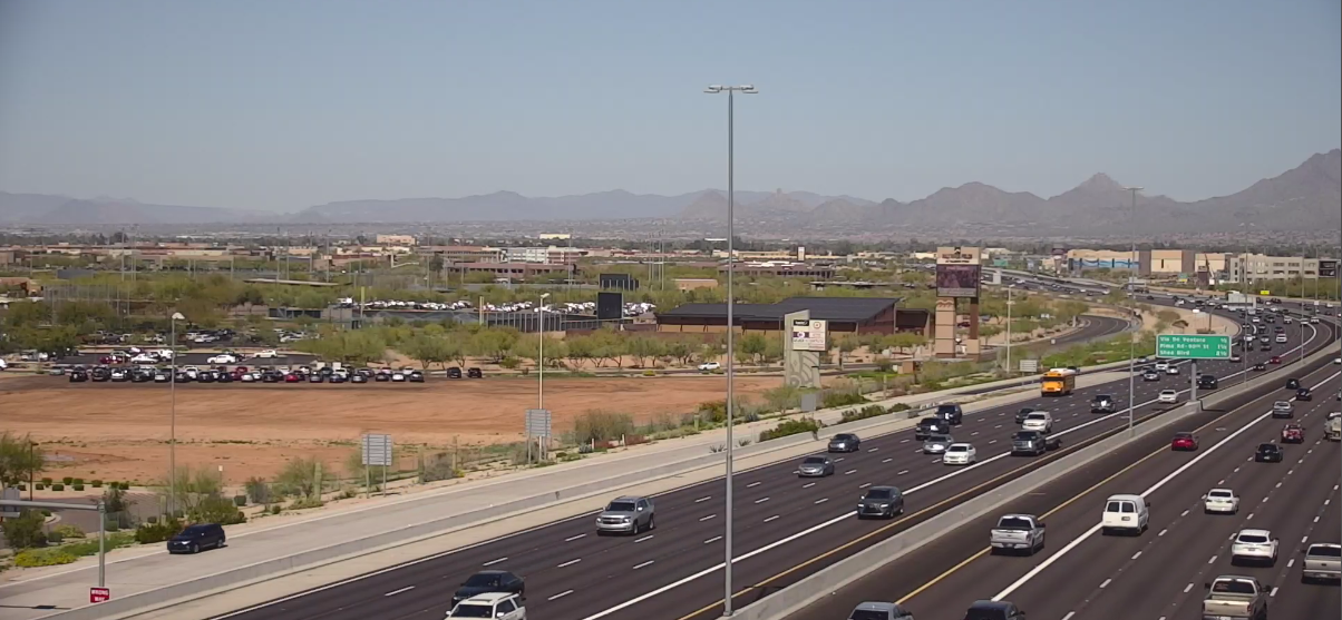Traffic camera image showing freeway traffic and stadium parking lot