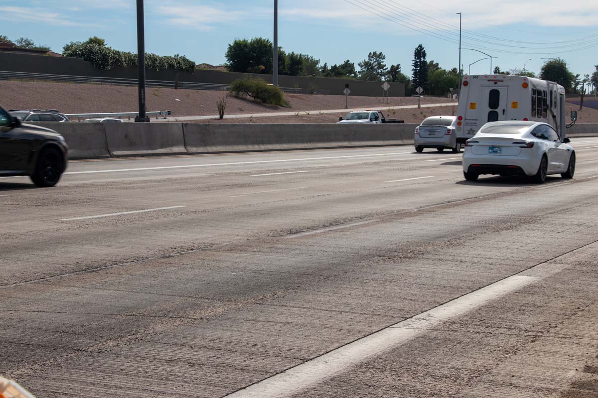 Traffic moving along Loop 101 near roadside landscaping and concrete barriers as construction continues.