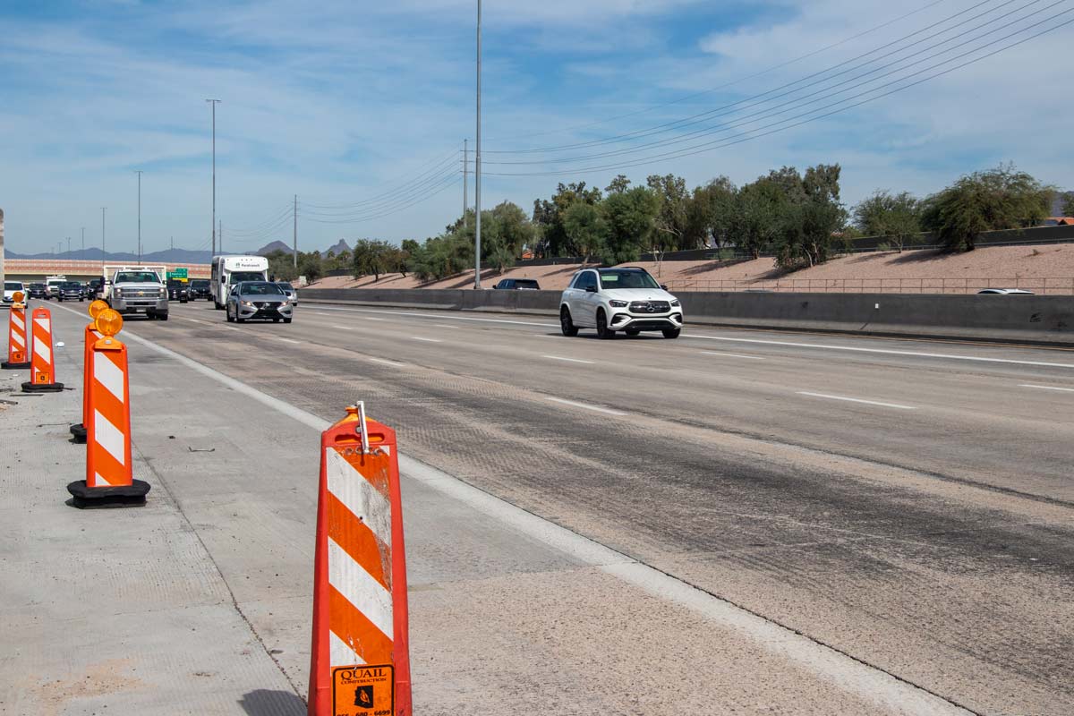 Construction cones and active traffic on Loop 101 during roadway widening and pavement improvement operations.