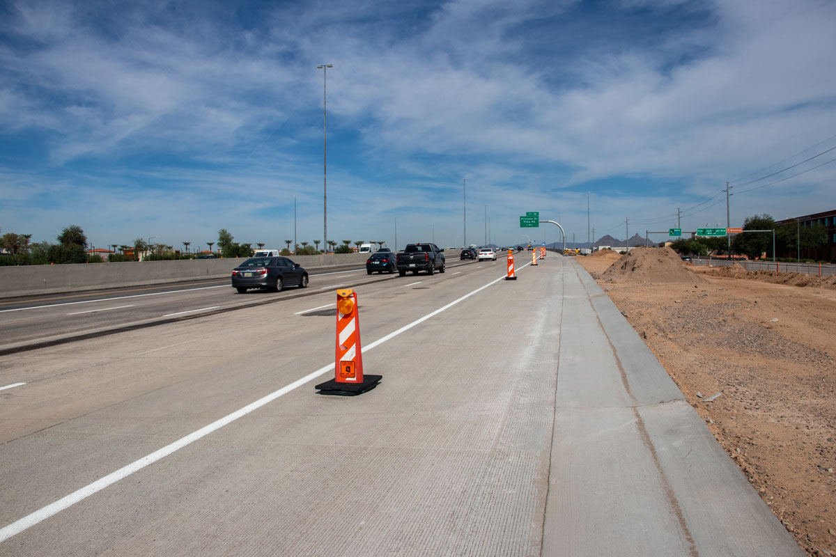 Traffic traveling on Loop 101 near Princess Drive exit with construction barrels and earthwork on the shoulder.