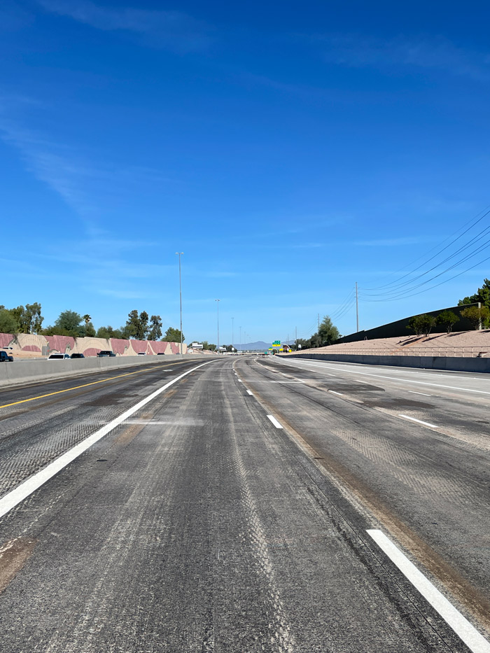 Newly planted ocotillo and desert landscaping in the Loop 101 median with traffic moving on both sides.