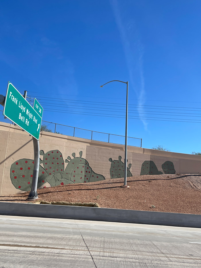 Loop 101 exit ramp for Frank Lloyd Wright Boulevard and Bell Road with a prickly pear cactus mural on the retaining wall.