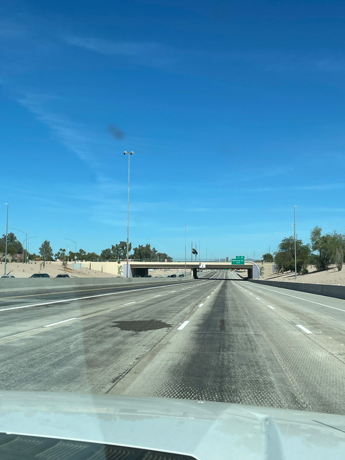 View of Loop 101 freeway with noise barriers and desert landscaping under clear blue skies during improvement work.