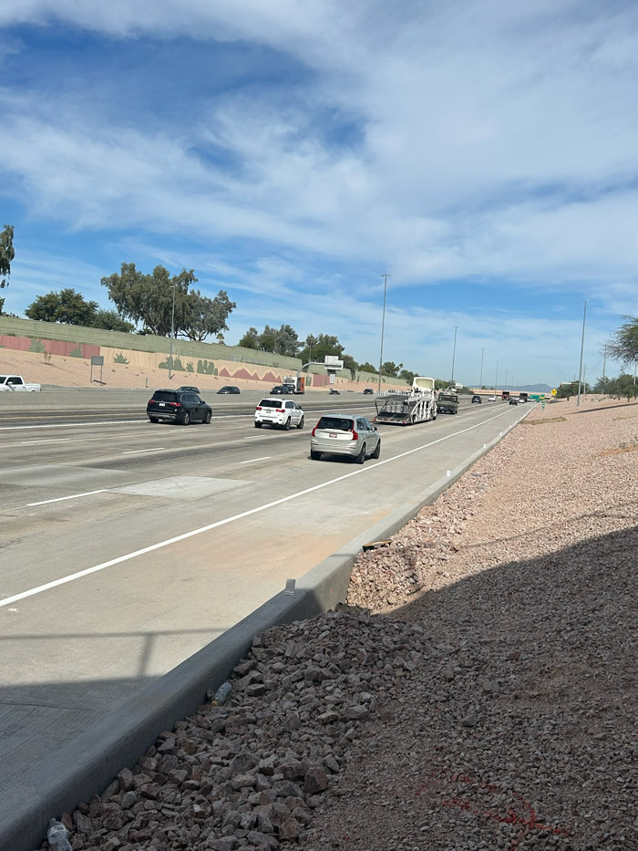 Vehicles traveling along Loop 101 with visible pavement wear and desert-themed wall murals in the distance.
