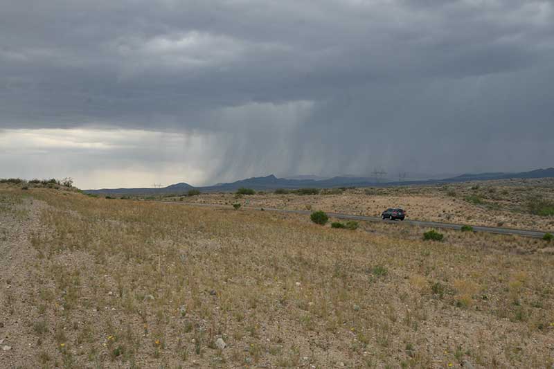 View of distant storm over grassland