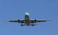 A commercial airplane is flying in a clear blue sky, viewed from below with its landing gear extended and wings level.