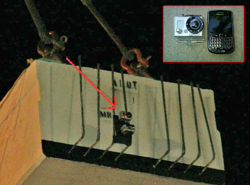 A small camera is attached to the side of a concrete block suspended by cables; an inset shows a camera and a mobile phone on a flat surface.